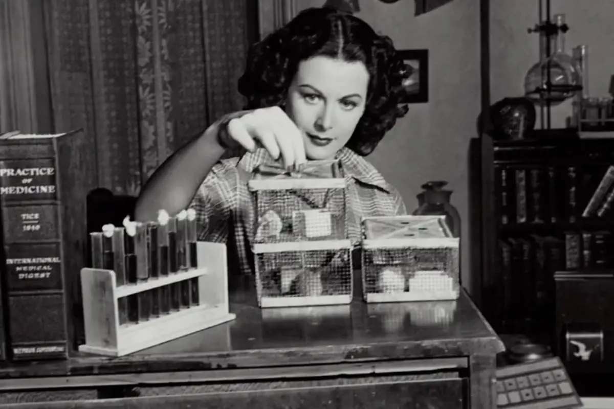 Hedy Lamarr, atriz e inventora, em um ambiente de laboratório, mexendo em equipamentos científicos, simbolizando suas contribuições como co-inventora do salto de frequência, precursor de tecnologias como Wi-Fi